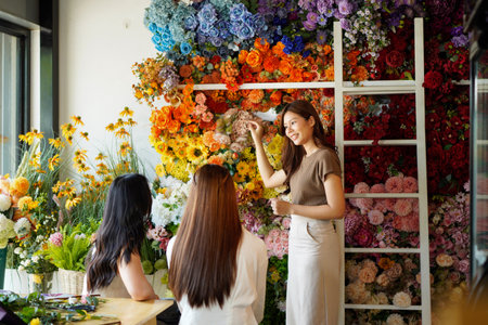 Diverse group of young people arranging flowers in florists workshop while attending class on floral art.の写真素材