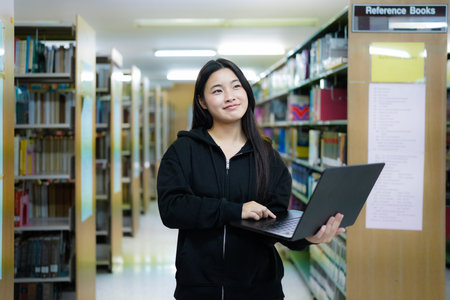 Young college woman working on his computer while studying in the library alone..