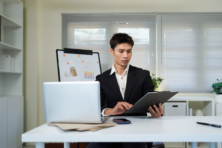 Serious businessman working on laptop. Male professional is planning strategy while sitting at office desk..の写真素材