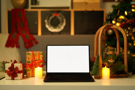 Front view of white screen laptop in home with Christmas tree warm light. Remote work. freelance. Work from home. Telework..の写真素材