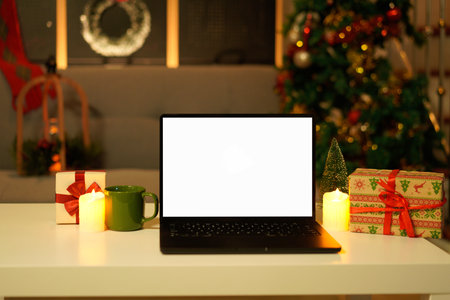 Blank display screen laptop computer on white wood table. Modern cozy comfortable home living room with Christmas decor. Home office desk workspace..の写真素材