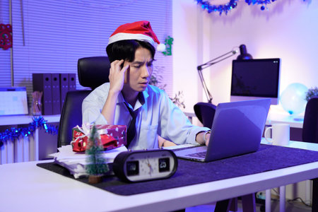Young businessman feeling burnout working late during Christmas.の写真素材