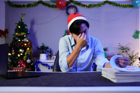 Young businessman feeling burnout working late during Christmas.の写真素材
