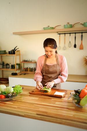 Happy smiling woman in the kitchen preparing a healthy lunch, breakfast, snack with organic...