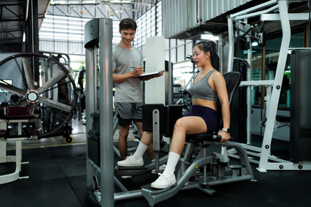 woman wear sportswear warm up training pull using leg trainer in gym indoor with personal trainer...