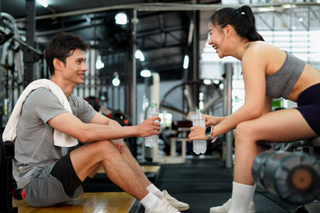Asian woman and man sit in fitness gym with relax activity also look happiness after training and practice in fitness gym..の写真素材