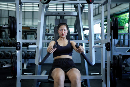 woman exercises on chest press machine. Client performs exercises, combines dynamic and static loads on body..の写真素材