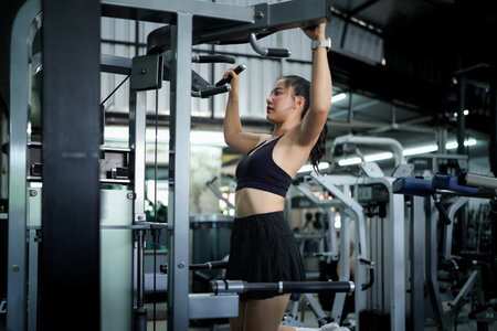 A woman is hanging from a bar at a gym.