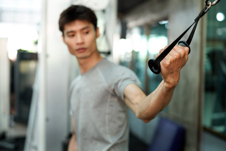 man doing strength training workout on a cable machine in a gym. Bodybuilder building muscle....