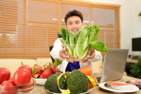 Nutritionist giving working on laptop and consultation to patient with healthy fruit and vegetable, Right nutrition and diet concept.の写真素材