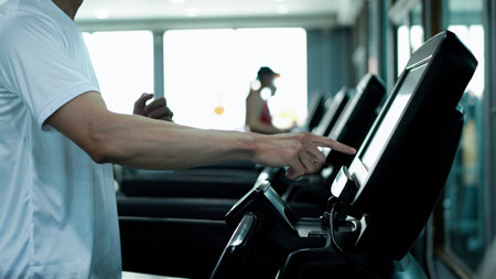 Man's finger adjusts settings, increasing speed or starting a workout in a fitness center..