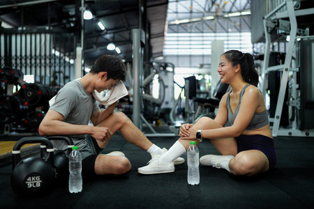 Fitness couple or friend having rest and talking, drinking water at gym.の写真素材
