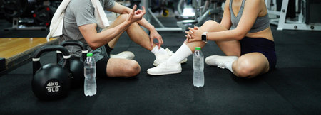 Fitness couple or friend having rest and talking, drinking water at gym.