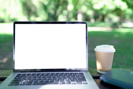 Mock up laptop computer, coffee cup on wooden table in the green garden..の写真素材