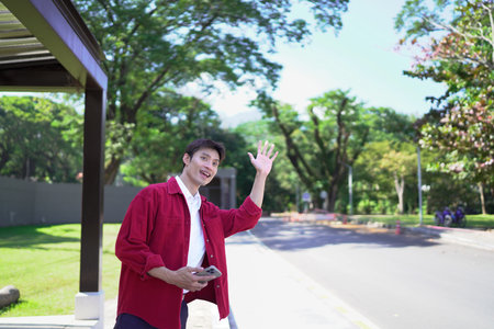 Asian man holding smartphone and meeting friends in evening street.の写真素材