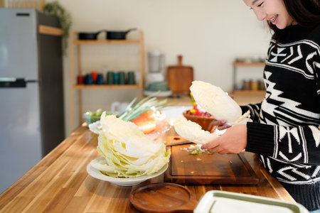 Woman cooking at home holds a fresh cabbage among colorful vegetables today.の写真素材