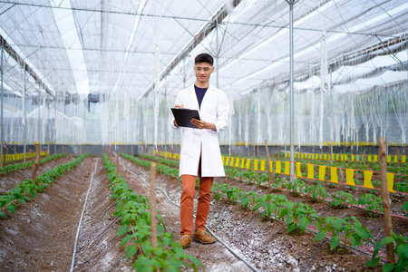 Agricultural Researcher Documenting Plant Growth Observations on a Clipboard in a Greenhouse..
