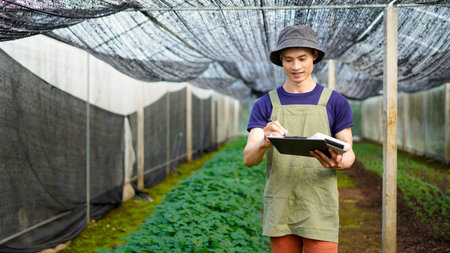 Farmer checking crops quality in greenhouse.