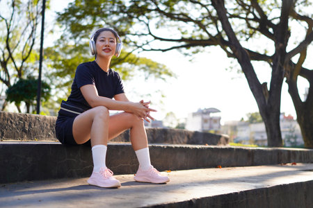woman, headphone and music in a park for exercise break in a park to rest by a tree. Workout.の写真素材