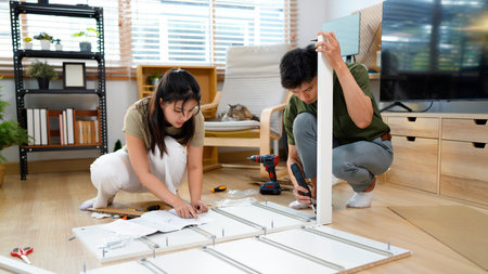 Young couple installing furniture in new house with instruction.の写真素材