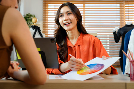 Two fashion designers working together on color palettes in a modern studio, highlighting creativity, teamwork, and a professional design.の写真素材