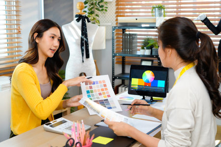 Two fashion designers working together on color palettes in a modern studio, highlighting creativity, teamwork, and a professional design.の写真素材