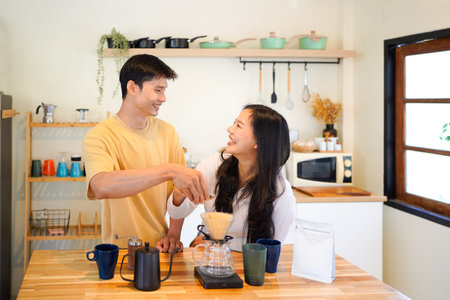 Happy couple making a drip coffee in kitchen together in home kitchen for a breakfast, A warm domestic lifestyle moment showing a romantic morning routine, brewing caffeine, and bonding with love.の写真素材