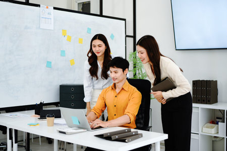 Three business people meet in modern office. Look at laptop, discuss project strategy, new plans....