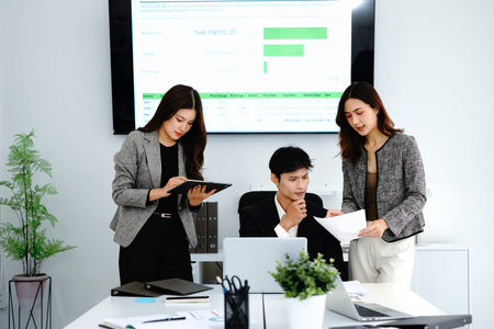 Three business people meet in modern office. Look at laptop, discuss project strategy, new plans....