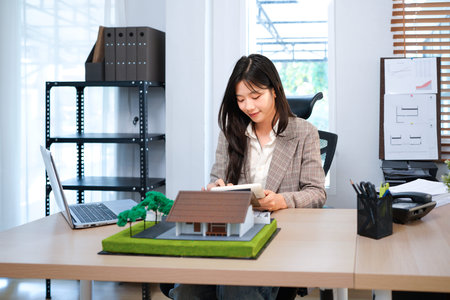 Business mortgage realtor with house model, sitting at desk, real estate agent manager working on...