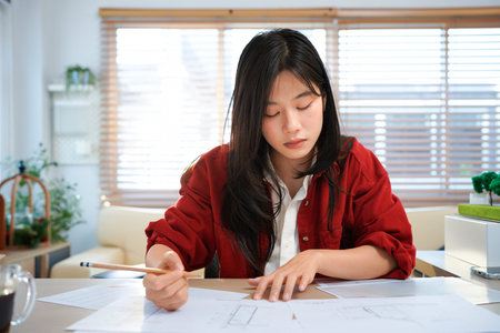 Young asian woman architect working in office with blueprints.Engineer inspect architectural plan,...