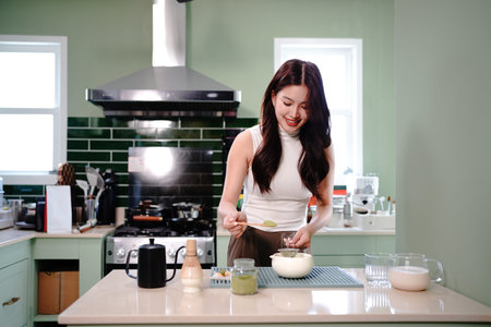Young Asian woman carefully scooping matcha powder into a traditional tea bowl in a calm and...