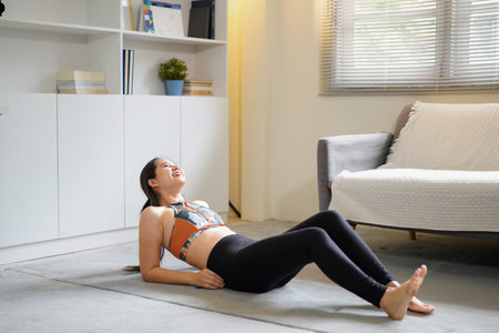 Sporty fit young woman relaxing on yoga mat at home.
