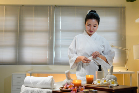 A young woman in a spa removes her bathrobe, preparing for a massage. Herbal compress and...