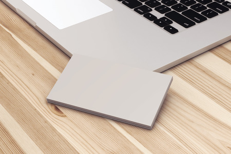Blank business cards with laptop on wooden office table.の写真素材