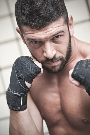 Portrait of muscular male boxer posing in boxing stance against grid background.の写真素材