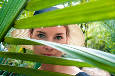Female portrait with palm branch leaves on foreground