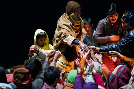 VARANASI, UTTAR PRADESH, INDIA  - JANUARY 15: Hindu man offered prasad to poor people after Ganga Maha Aarti ceremony at Dashashwamedh Ghat on January 15, 2010 in Varanasi, Indiaのeditorial素材