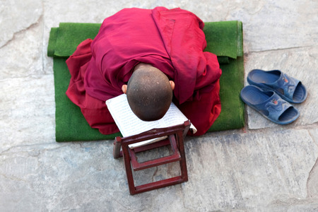 KATHMANDU, NEPAL - NOVEMBER 18: Young Buddhist monk praying at Swayambhunath monastery cortyard on November 18, 2009 in Kathmandu, Nepal.のeditorial素材