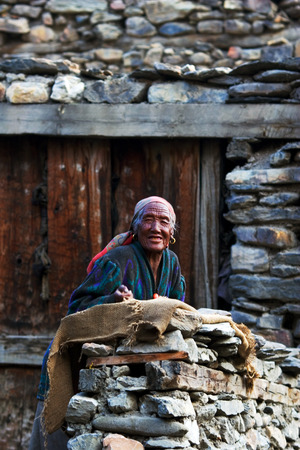 ANNAPURNA CIRCUIT, NEPAL - APRIL 23: Old tibetian woman from the village of tibetan refugees on the doorstep of his homel in the Himalayas, Nepal on 23 April 2008.のeditorial素材