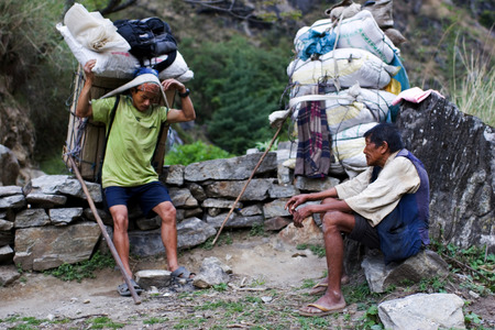ANNAPURNA CIRCUIT, NEPAL - APRIL 20: Two porters carrying heavy load in the Himalaya, Nepal on 20 April 2008.のeditorial素材