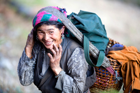 LHO, GORKHA, NEPAL - NOVEMBER 20: Tibetan woman walking back home after a long day's work in the field  on November 20, 2009 in Lho village, Nepal.のeditorial素材