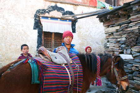 MU GOMPA, TSUM VALLEY, NEPAL - NOVEMBER 23: Three young buddhist monks with horse poses for a photo at Mu Gompa Monastery on November 23, 2009 in Tsum Valley, Nepal.のeditorial素材