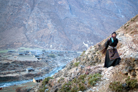GORKHA, NEPAL - NOVEMBER 23: Tibetan peasant woman with basket in the Himalaya on November 23, 2009 in Tsum Valley, Manaslu restricted area, Nepal.のeditorial素材