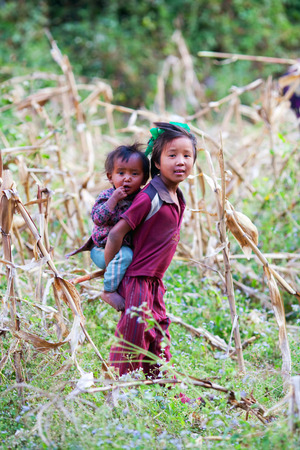 PHILIM, GORKHA, NEPAL - NOVEMBER 18:  Nepalese girl Sonam, 8, carries her baby sister in a corn field on November 18, 2009 in Philim village, Nepal.のeditorial素材
