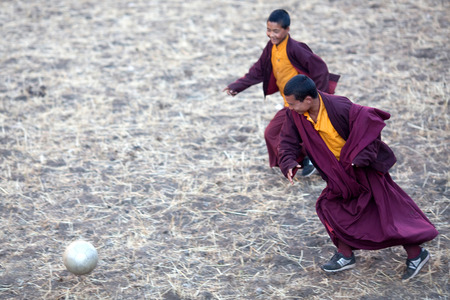 GORKHA, NEPAL - NOVEMBER 28: Two young buddhist monks playing soccer at the monastery courtyard on November 28, 2009 in Gorkha District, Manaslu Area, Nepal.のeditorial素材