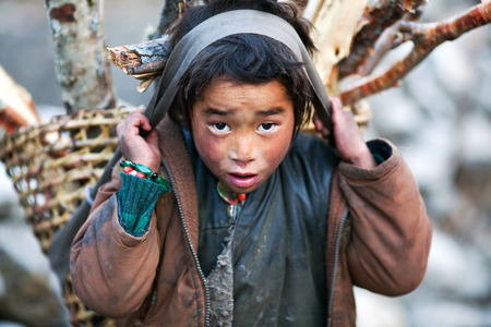 LHO, GORKHA, NEPAL - NOVEMBER 29: Tibetan boy with basket of firewood poses for a photo on the road to Lho village on November 29, 2009 in Gorkha District, Nepalのeditorial素材
