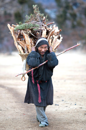 GORKHA, NEPAL - NOVEMBER 28: nepalese man carrying heavy basket in the Himalaya on november 28, 2009 in Gorkha District, Manaslu Area, Nepalのeditorial素材