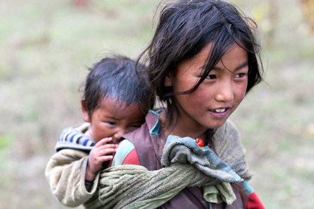 DHO TARAP, NEPAL - SEPTEMBER 10: Tibetan girl with her baby brother walkig on the road on September 10, 2011 in Dho Tarap village, Upper Dolpo, Nepalのeditorial素材