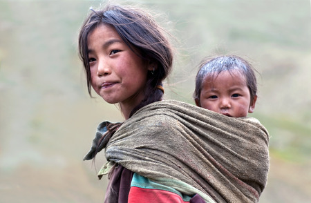 DHO TARAP, NEPAL - SEPTEMBER 10: Tibetan girl with her baby brother walkig on the road on September 10, 2011 in Dho Tarap village, Upper Dolpo, Nepalのeditorial素材